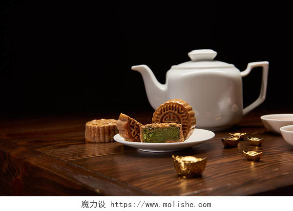 传统美味的中国月饼茶壶和金锭在木桌上隔离在黑色八月十五中秋节月饼中秋节